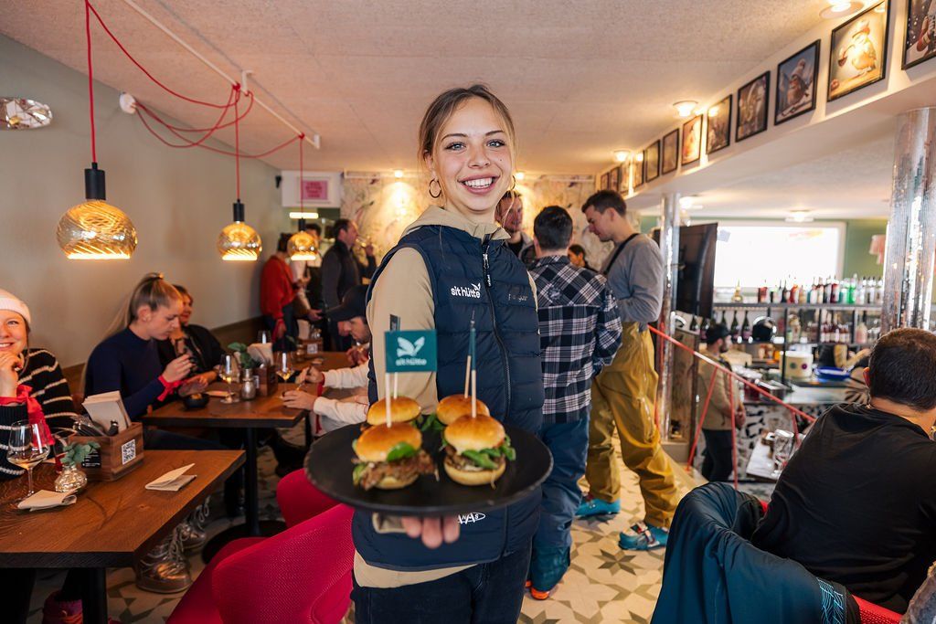 Mitarbeiterin serviert Mini-Burger in der vollen Hütte