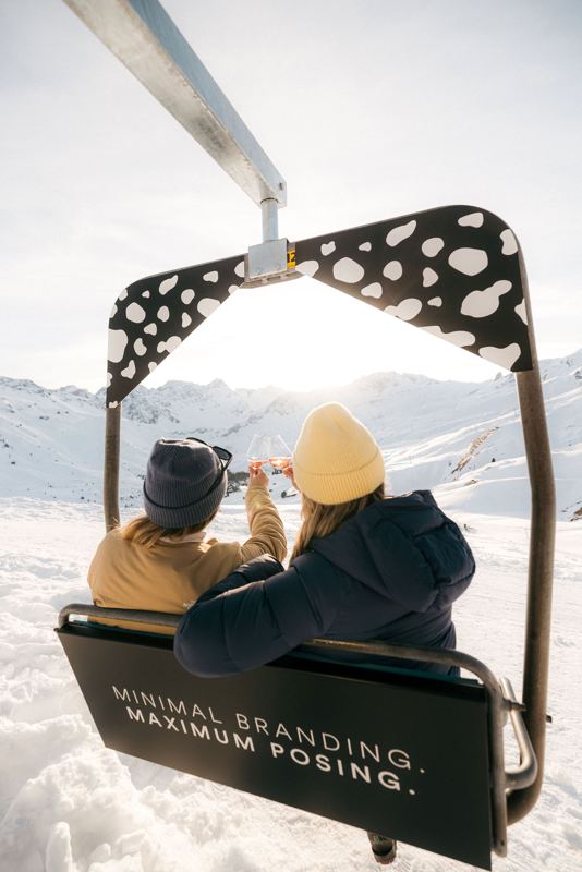 Zwei Gäste im Sessellift mit sit-hütte-Branding