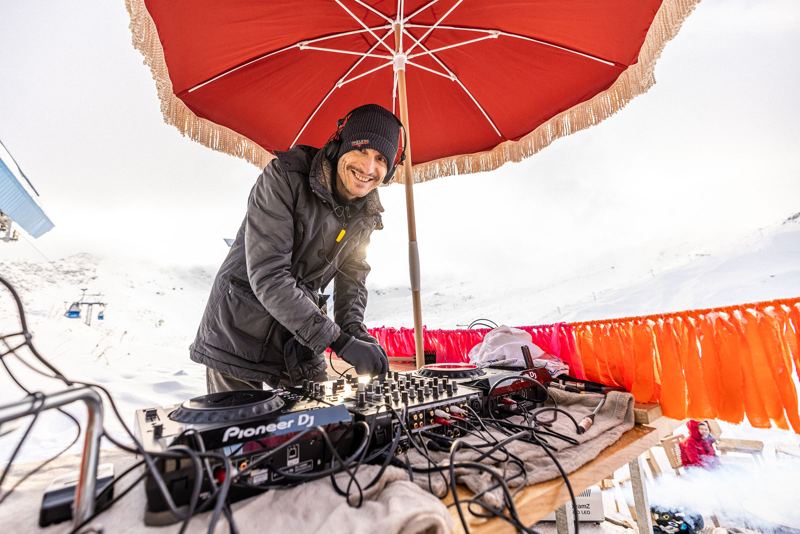 DJ unter rotem Sonnenschirm auf der Terrasse